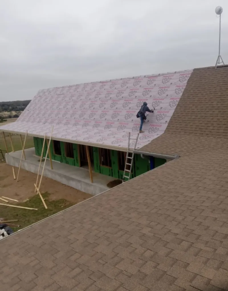 Worker preparing underlayment for a metal roof installation in Alpena